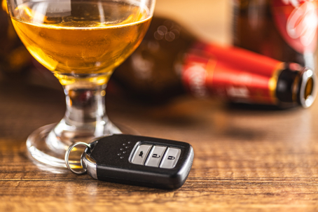 Car key with beer glass on a wooden table.